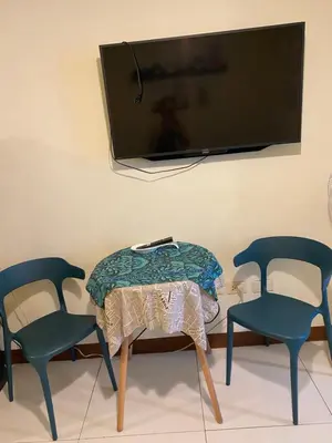 a living room with two chairs and a table and a tv at The Teal Deal in Manila