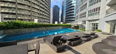 a swimming pool with chairs and a table and some buildings at Your HOME away from home in Manila