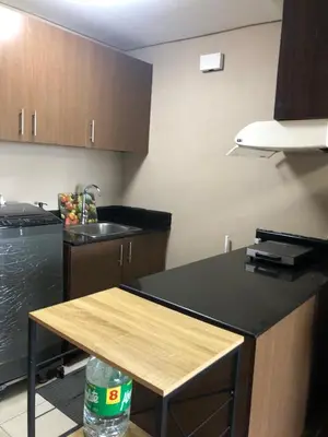 a kitchen with a black counter top and wooden cabinets at A Venue Residences Tower 12L in Manila