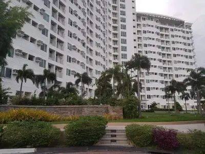 a large apartment building with palm trees in front of it at Anuva Staycation by Gina in Manila