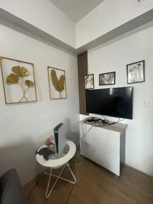 a living room with a tv and a desk with a computer at Anuva Staycation by Gina in Manila