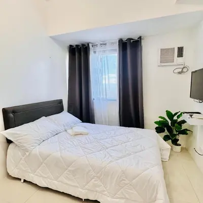 a bedroom with a white bed with black curtains at New Condo at Grand Riviera Suites across US Embassy in Manila