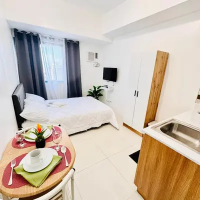 a room with a bed and a table and a kitchen at New Condo at Grand Riviera Suites across US Embassy in Manila