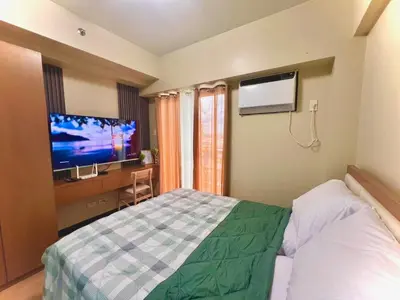 a hotel room with a bed and a flat screen tv at Calathea Luxe Atrium Suite in Manila