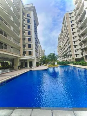 a large swimming pool in the middle of two buildings at Calathea Luxe Atrium Suite in Manila