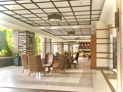 a lobby with chairs and a table and a restaurant at Calathea Luxe Atrium Suite in Manila