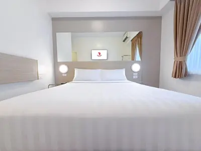 a bedroom with a large white bed and a window at Red Planet Makati Amorsolo in Manila