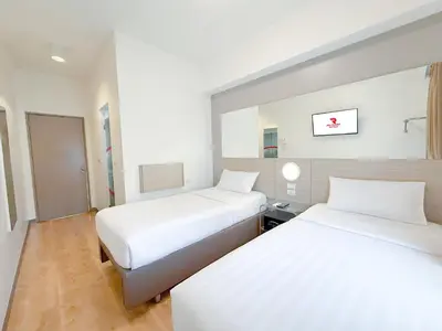 two beds in a room with white walls and wood floors at Red Planet Makati Amorsolo in Manila