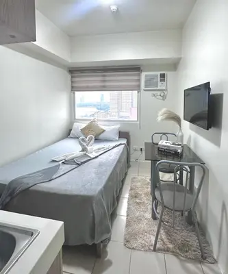 a small bedroom with a bed and a television at Jam Reid Condotel Mandaluyong in Manila