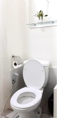 a bathroom with a white toilet with a plant on a shelf at Jam Reid Condotel Mandaluyong in Manila