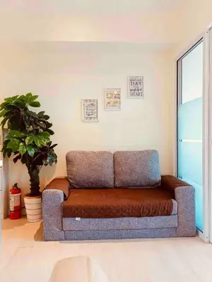 a couch in a living room with a plant at Upscale 1Bedroom Condo Unit Near Manila Airport in Manila