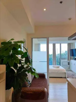 a living room with a plant and a bedroom at Upscale 1Bedroom Condo Unit Near Manila Airport in Manila