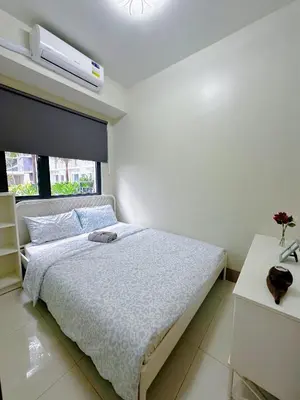 a white bedroom with a bed and a window at The Ilongga Haven 3 Staycation at Mall of Asia in Manila