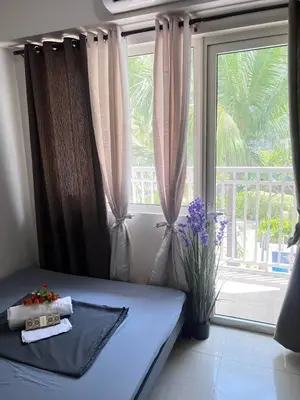a bedroom with a bed and a large window at Unistay SHORE Residence amazing pool view in Manila