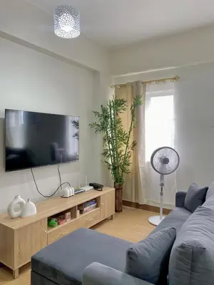 a living room with a blue couch and a flat screen tv at Casa Maria Staycation SMDC Hope Residences in Trece Martires
