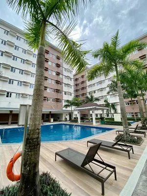 a hotel with a swimming pool and palm trees at Casa Maria Staycation SMDC Hope Residences in Trece Martires