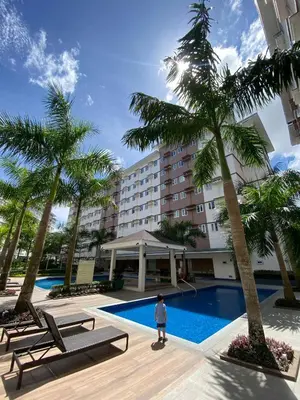 a person standing in front of a hotel with a pool at Casa Maria Staycation SMDC Hope Residences in Trece Martires