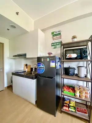 a kitchen with a refrigerator and a shelf with food at Casa Maria Staycation SMDC Hope Residences in Trece Martires