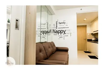 a living room with a couch with a happy wall at MOA city view in Manila