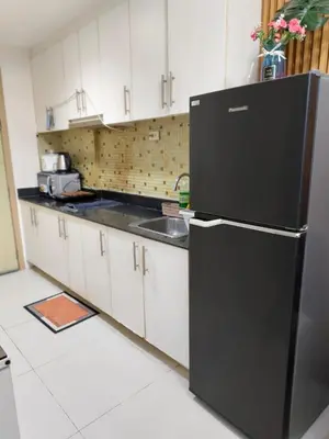 a kitchen with a black refrigerator and a sink at Sea Residence MOA - JULIZA STAYCATION in Manila