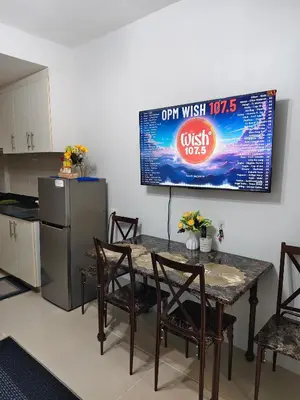 a kitchen with a table with chairs and a tv at Sea Residence MOA - JULIZA STAYCATION in Manila