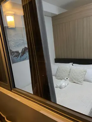 a reflection of a bedroom with a bed and a mirror at 12 Minutes from Mall of Asia - Spacious Condo with Balcony & Hot Shower in Manila