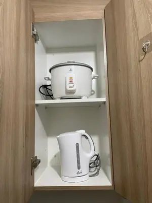 a cabinet with a pot and a toaster in it at 12 Minutes from Mall of Asia - Spacious Condo with Balcony & Hot Shower in Manila