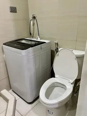 a bathroom with a white toilet and a sink at 12 Minutes from Mall of Asia - Spacious Condo with Balcony & Hot Shower in Manila