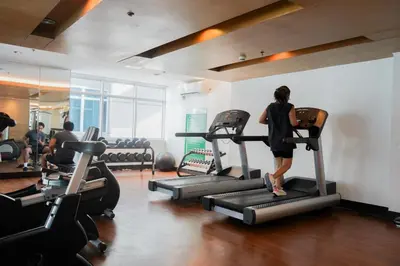 a woman walking on a treadmill in a gym at Beautiful 1-Bedroom Condo in Makati - Pool, Gym & Near Airport in Manila