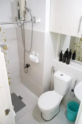 a white bathroom with a toilet and a shower at Beautiful 1-Bedroom Condo in Makati - Pool, Gym & Near Airport in Manila