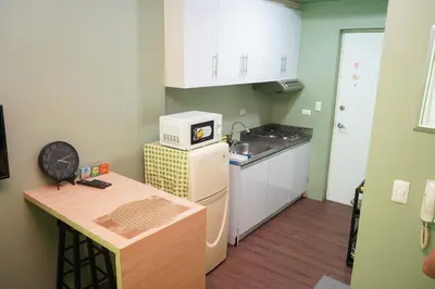a small kitchen with a sink and a microwave at Beautiful 1-Bedroom Condo in Makati - Pool, Gym & Near Airport in Manila