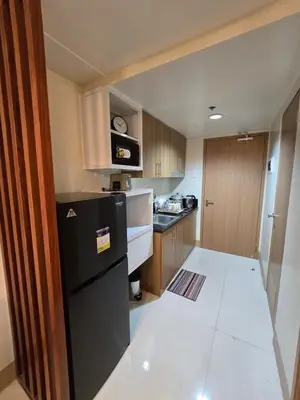 a small kitchen with a black refrigerator and cabinets at Shore 3 Residences tower 3 in Manila