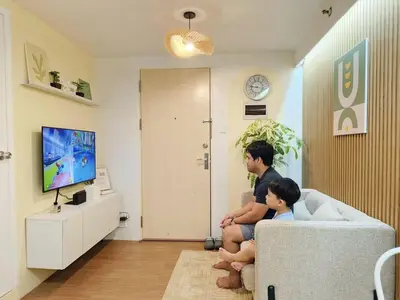 a man and a child sitting on a couch watching tv at 2BR Pasig Condo for Family or Group with Parking in Manila