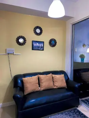 a black leather couch in a living room with three mirrors at Yumi Azure Staycation in Manila