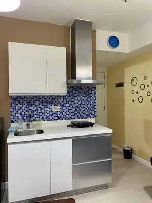 a kitchen with white cabinets and a sink at Yumi Azure Staycation in Manila