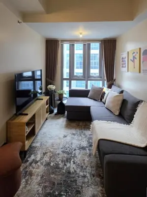 a living room with a couch and a television at Funky HQ - 1BR Eastwood Global Plaza in Manila
