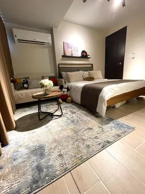 a bedroom with a bed and a table with a rug at Funky HQ - 1BR Eastwood Global Plaza in Manila