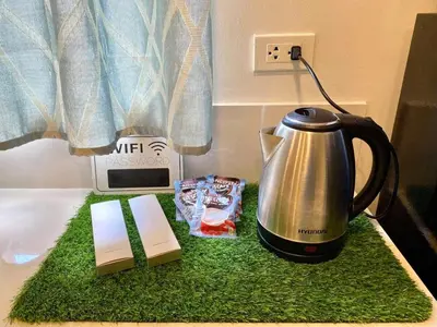 a tea kettle and a clock on a bed at Cozy Studio Sorrento Oasis Rosario Pasig in Manila