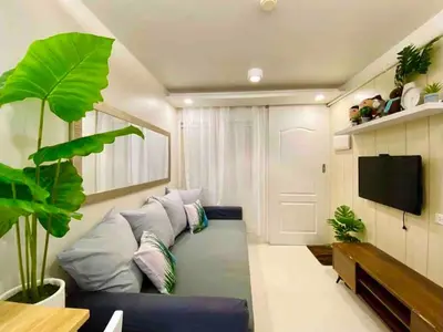 a living room with a blue couch and a tv at Cozy Studio Sorrento Oasis Rosario Pasig in Manila