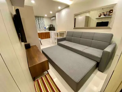 a living room with a couch and a kitchen at Cozy Studio Sorrento Oasis Rosario Pasig in Manila