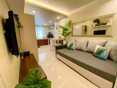 a living room with a couch and a kitchen at Cozy Studio Sorrento Oasis Rosario Pasig in Manila
