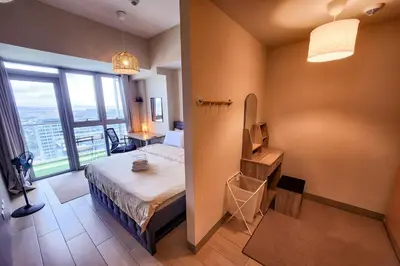 a bedroom with a bed and a large window at Travellers Haven 3br BGC, Bathtub, XBOX, 200mbps in Manila