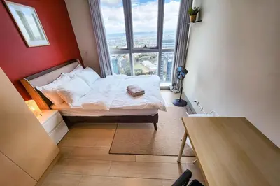 a bedroom with a bed and a large window at Travellers Haven 3br BGC, Bathtub, XBOX, 200mbps in Manila