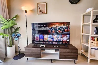 a tv in a living room with a desk at Travellers Haven 3br BGC, Bathtub, XBOX, 200mbps in Manila