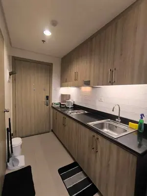 a kitchen with wooden cabinets and a sink and a toilet at EmFress Suites in Manila