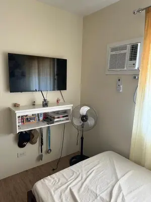 a bedroom with a bed and a tv and a fan at Stanford Suites 1 in Silang