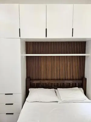 a bed with a wooden headboard and white cabinets at Condo in Coast Residences, Pasay City in Manila