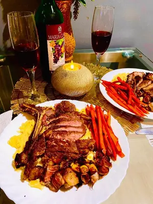 a plate of meat and vegetables on a table with wine at Man-made beach waves 19 minutes from NAIA in Manila