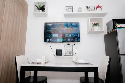 a white table with chairs and a tv on a wall at Staycation near Moa new room in Manila