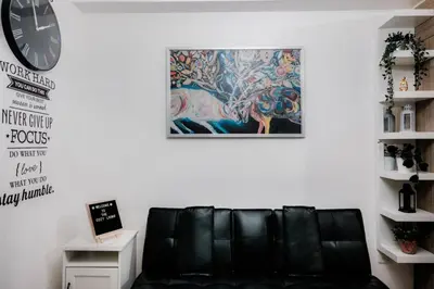 a black leather couch in a living room with a painting at Staycation near Moa new room in Manila